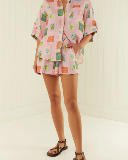 Full body shot of women's pink summer printed short sleeve short set with belt, styled with dark sandals.