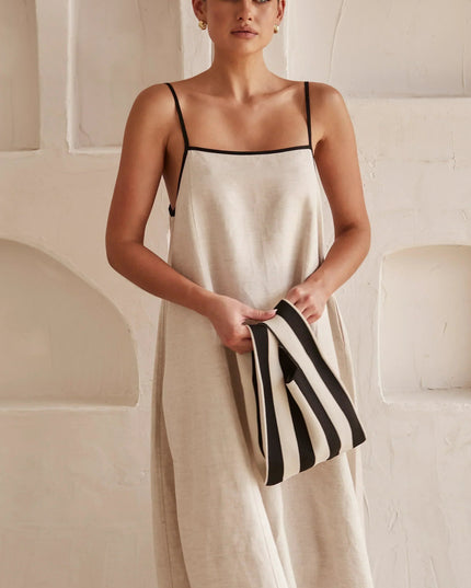 Close-up of the square neck and black spaghetti straps on a light beige women's maxi dress.