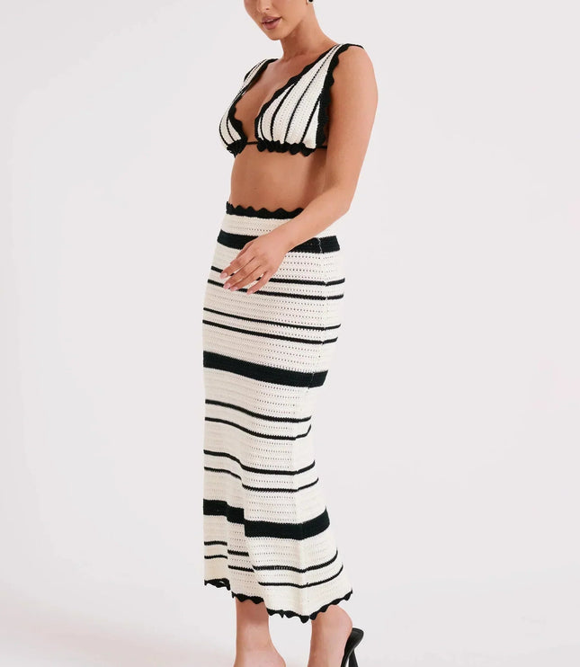 Side view of a women's black and white striped crochet two piece maxi set, showing the fitted skirt and crop top with scalloped trim.