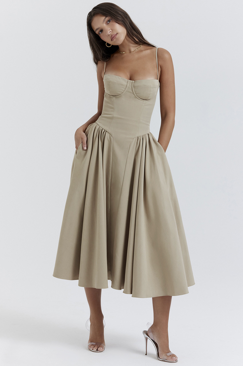Full-length view of a women's sweetheart neck corset midi dress in light khaki with deep pockets, paired with clear heels.