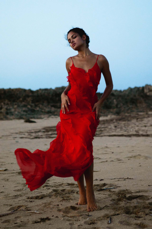 Red V-neck ruffle side slit maxi dress flowing on a beach, showcasing the airy fabric.