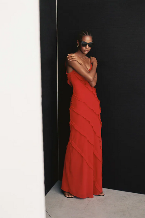 Front view of a red V-neck ruffle side slit maxi dress with layered ruffles and thin straps, worn with sunglasses