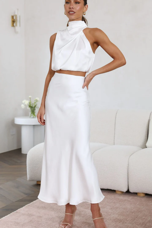 Full length view of women's white satin asymmetrical high neck crop top and elegant maxi skirt set, a chic wedding suit.