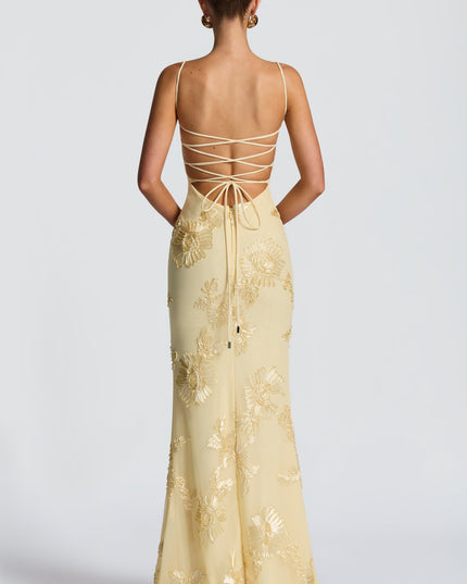 Rear view of a light yellow floral maxi dress showing the lace-up back detail and gold embroidered flowers.