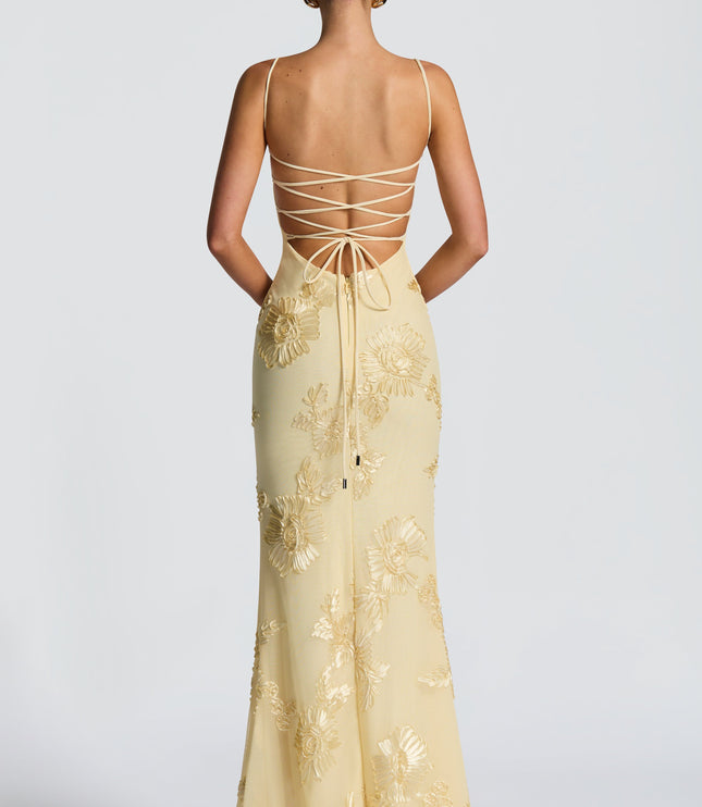 Rear view of a light yellow floral maxi dress showing the lace-up back detail and gold embroidered flowers.