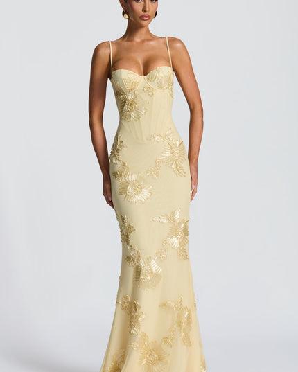 Front view of a woman standing in a light yellow floral corset maxi dress with gold embroidered details and a sweetheart neckline.
