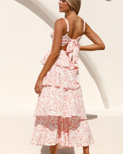Back view of a woman wearing the pink floral ruffled maxi dress, showcasing the tie-back detail and tiered skirt.
