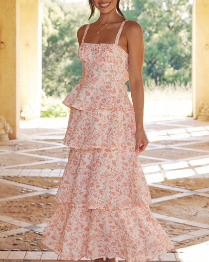 Full-length view of a woman in the pink floral ruffled maxi dress, smiling and standing in an arched hallway.