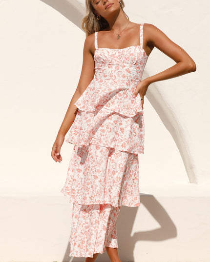 Woman posing confidently in the pink floral ruffled maxi dress, with hands on hips against a white wall.