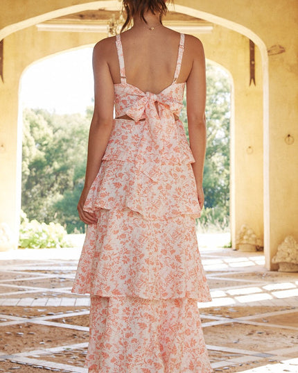 Back view of a women's pink floral ruffled maxi dress featuring a tie-back detail and tiered skirt.