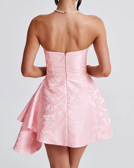Back view of a women's strapless pink floral jacquard mini dress with a zipper closure and ruffled detail, ideal for wedding guest attire.