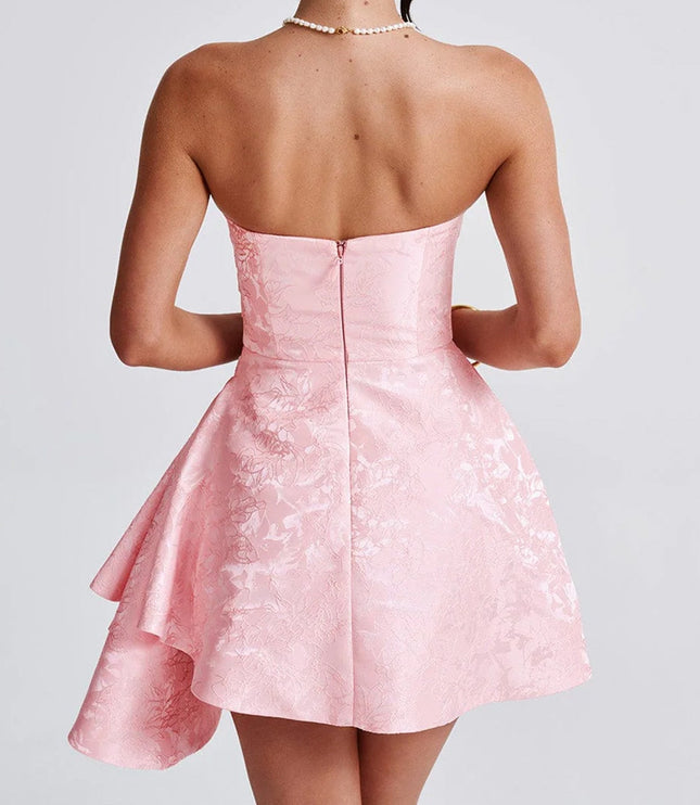 Back view of a women's strapless pink floral jacquard mini dress with a zipper closure and ruffled detail, ideal for wedding guest attire.