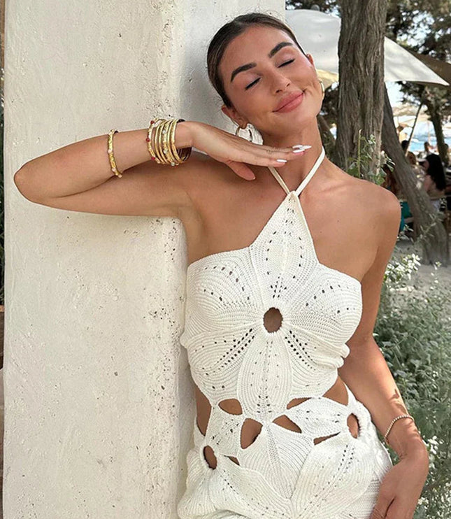 Close-up of a women's white crochet halter neck mini dress, showing the detailed floral pattern and side cut-outs.