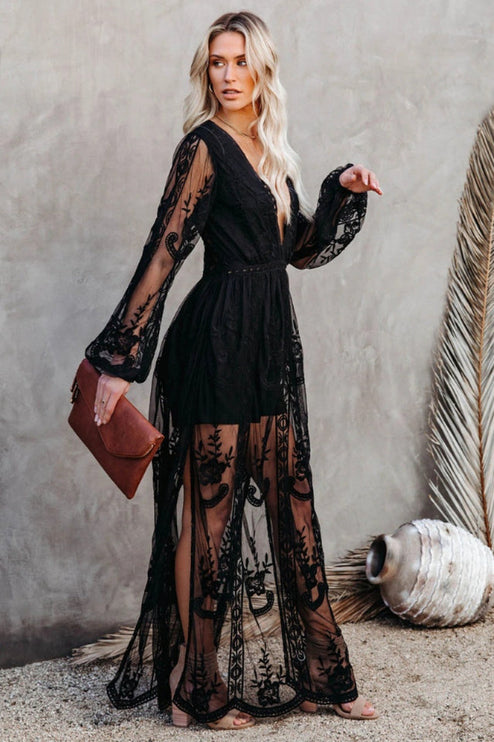 Three-quarter view of a women's black lace long sleeve V-neck maxi dress, showcasing the full length and sheer fabric.