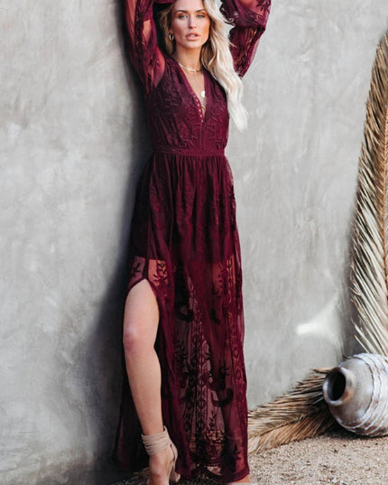 Side view of a burgundy lace long sleeve V-neck maxi dress, featuring a high slit and delicate floral patterns.