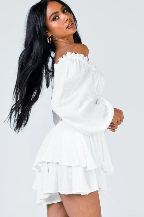 Dynamic side profile of white off-shoulder long sleeve mini dress, showcasing the smocked bodice and layered ruffled skirt details.