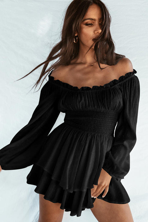 Black off-shoulder long sleeve mini dress with smocked waist and tiered ruffled skirt, featuring subtle textured dots.