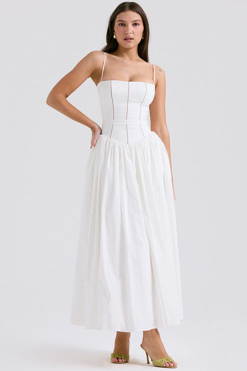 Women's white square neck midi dress with thin straps, structured bodice, and full pleated skirt, paired with green heels.