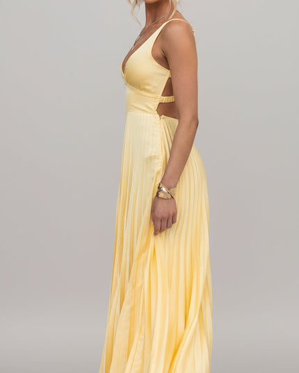 Side view of a yellow V-neck pleated maxi dress, highlighting the cut-out waist detail and clear heels.