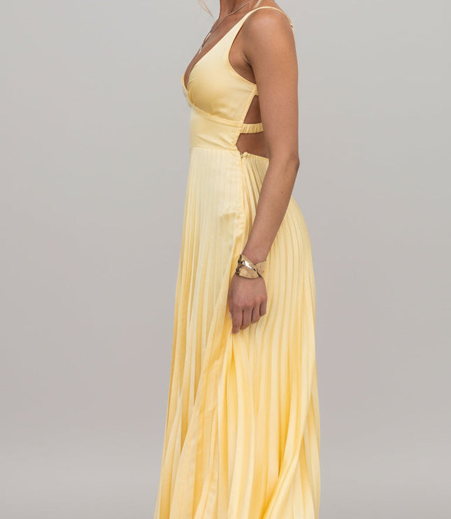Side view of a yellow V-neck pleated maxi dress, highlighting the cut-out waist detail and clear heels.