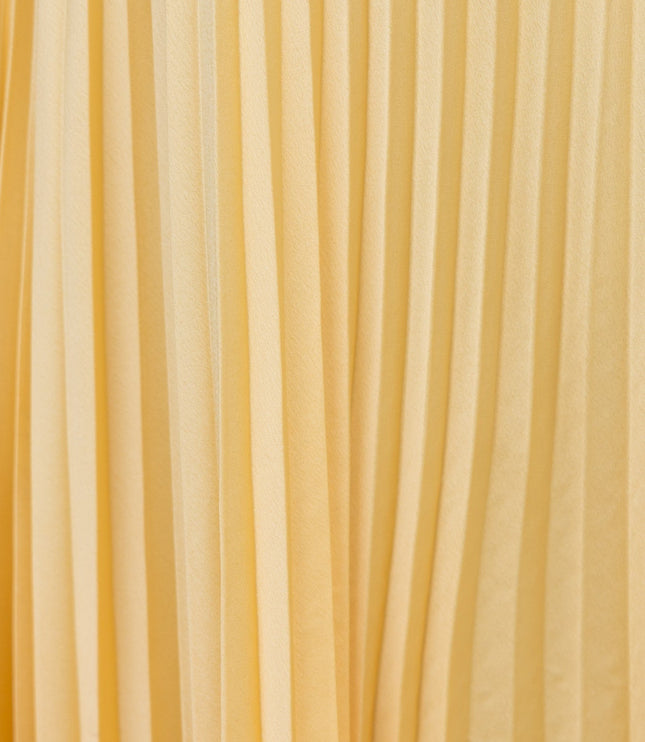 Close-up texture of the yellow pleated fabric on the maxi dress, showing vertical folds.