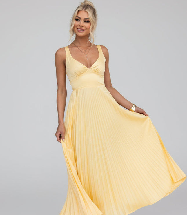Women's yellow V-neck pleated maxi dress with cut-out details, flowing skirt, and gold heels.